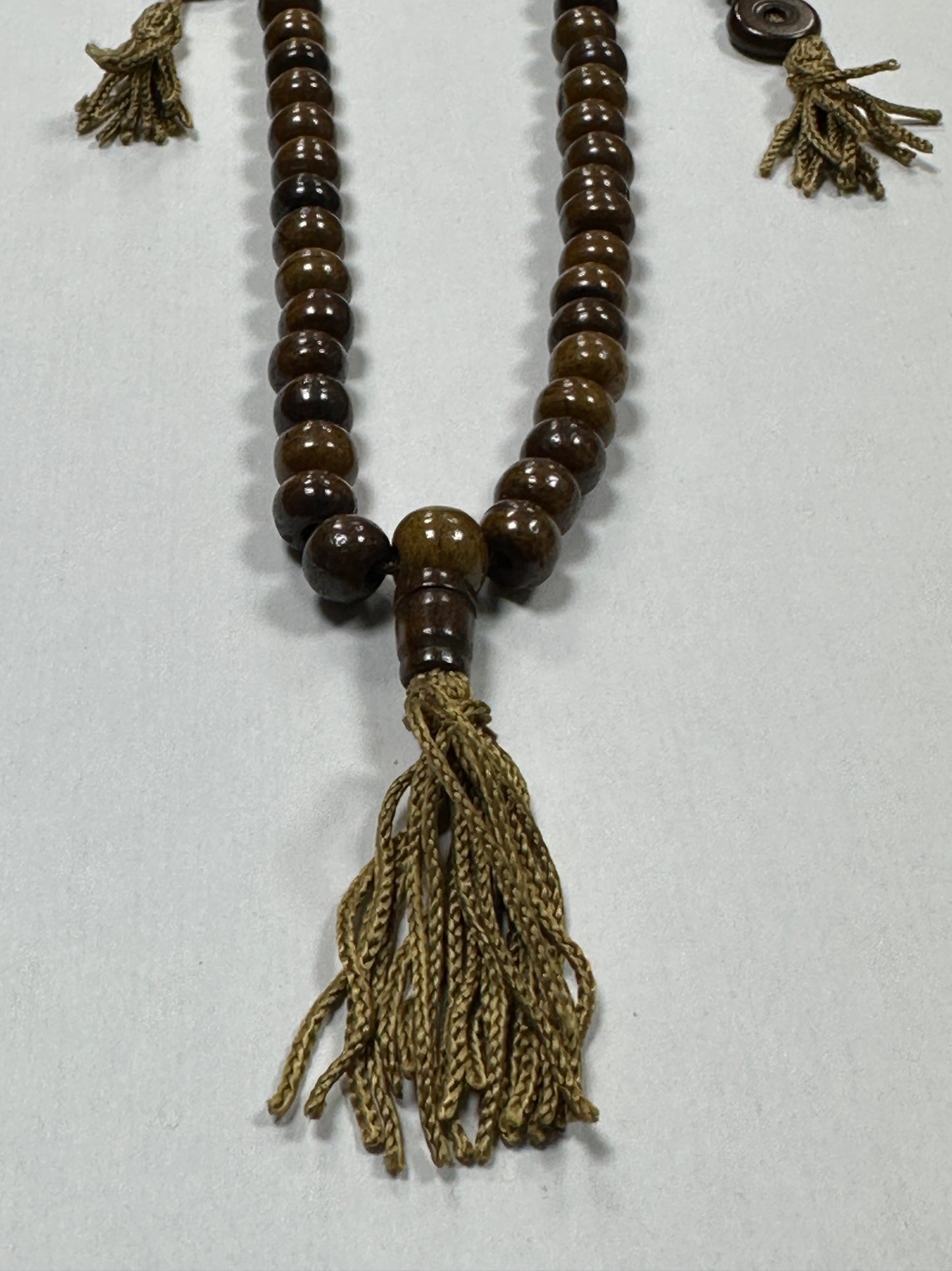 Brown prayer beads with tassels on a white background