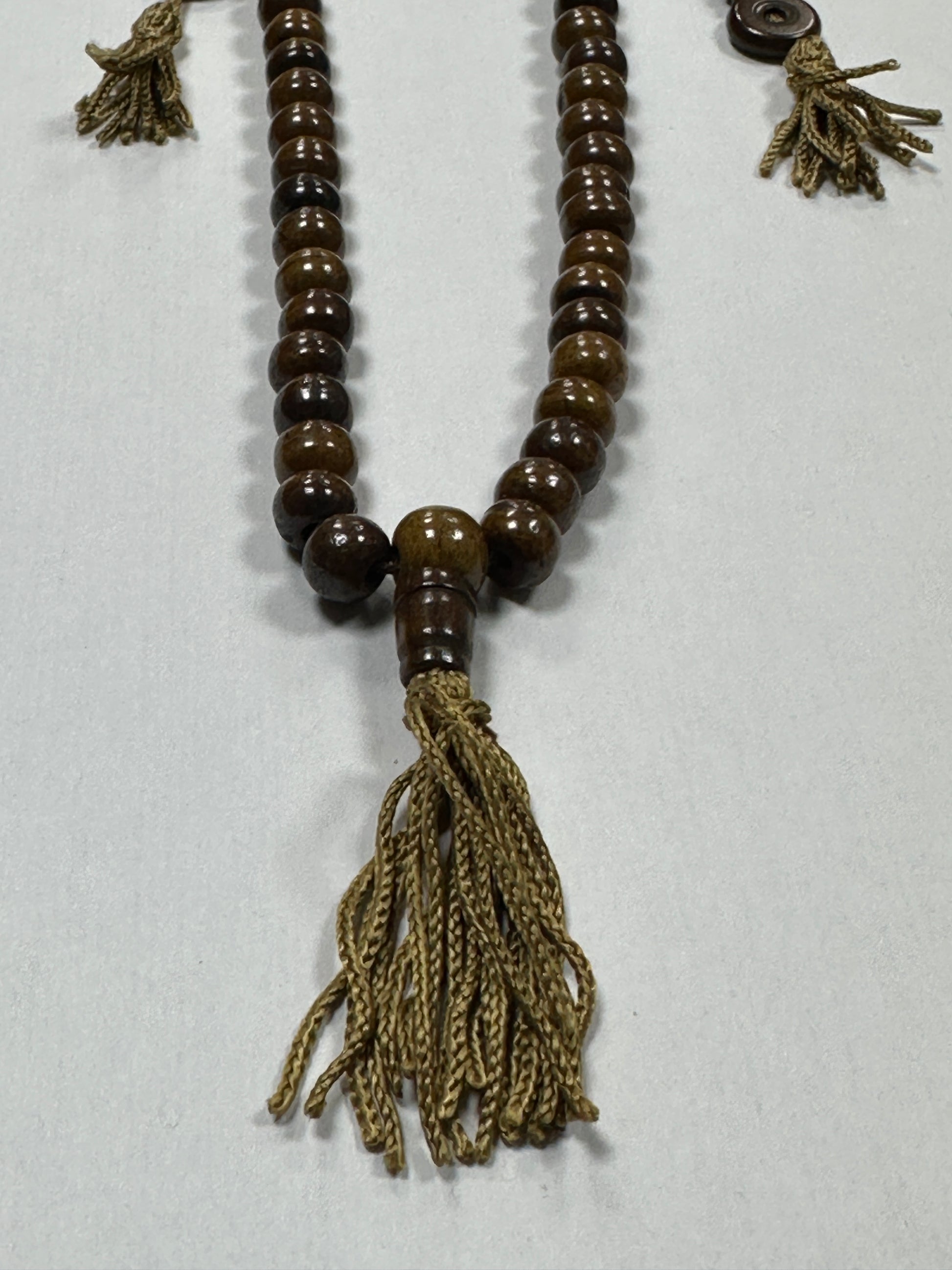 Brown prayer beads with tassels on a white background